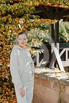 Beautiful elegant woman standing in autumn park with yellow leaves outdoor. Beauty Romantic Girl Outdoors enjoyitumn