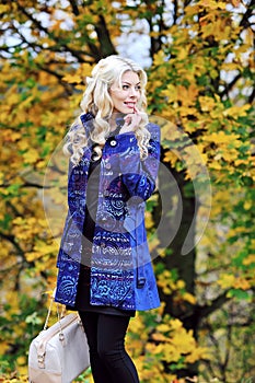 Beautiful elegant woman standing in a park in autumn