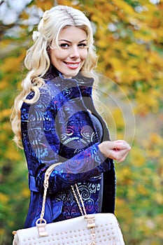 Beautiful elegant woman standing in a park in autumn