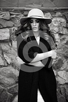 Beautiful elegant woman in stylish trendy black coat and hat ove
