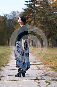 Beautiful elegant woman walking through a city park in autumn