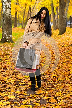 Beautiful elegant woman walking in the park with shopping