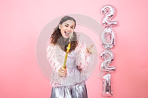 Young woman on a pink background with silver ballons in the form of the numbers 2021 photo