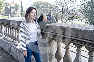 Beautiful and elegant young business woman waiting leaning against an old railing in a 19th century esplanade