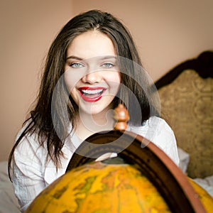 Beautiful elegant young woman attractive brunette female student happy smiling with red lipstick at the globe looking at camera