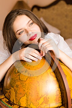 Beautiful elegant young woman attractive brunette female student happy smiling with red lipstick at the globe looking up