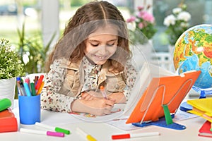 Beautiful emotional girl draws with colored pencils. At the table.