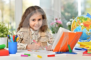 Beautiful emotional girl draws with colored pencils. At the table.