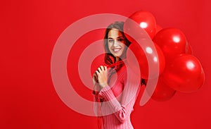 Beautiful emotional girl in pink dress with red ballons on red background