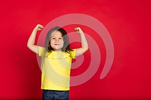 Beautiful emotional little girl  on red background. Half-lenght portrait of happy child gesturing