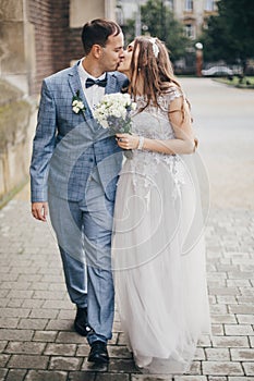 Beautiful emotional wedding couple kissing and walking in european city. Provence wedding. Stylish happy bride and groom walking