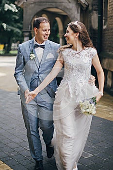 Beautiful emotional wedding couple smiling and walking in european city. Provence wedding. Stylish happy bride and groom walking