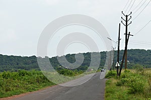 Beautiful Empty road in Autumn season with green fields and cloudy sky in Goa