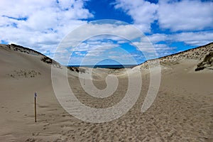 Beautiful endless sand dunes on the baltic sea coast under bright blue sky with clouds, Curonian Spit, Lithuania