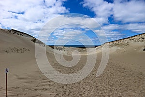 Beautiful endless sand dunes on the baltic sea coast under bright blue sky with clouds, Curonian Spit, Lithuania