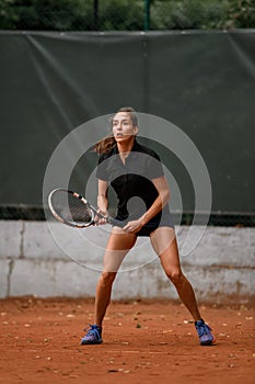 Beautiful energy female tennis player with racket ready to hit tennis ball.