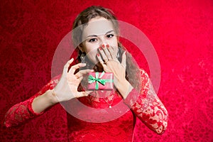 Beautiful enthusiastic girl with a small gift in a red dress