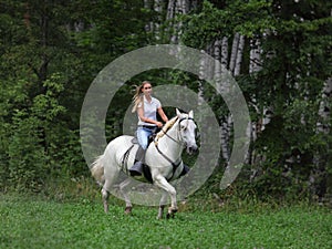 Beautiful equestrian cowgirl riding a horse in the summer forest photo