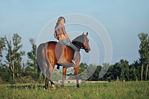 Beautiful equestrian girl bareback ride her horse in woods glade at sunset