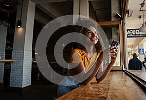 Beautiful ethnic women gazing upward and sitting at window sill of eco coffee shop.