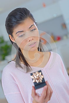 beautiful eurasian woman looking at enagement ring and doubting