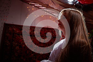 Beautiful European girl looking like Arab woman in red room with rich fabrics and carpets in sultan harem. Photo shoot