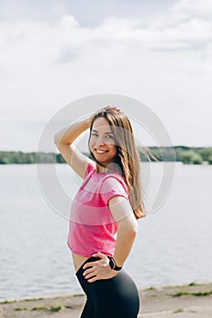 Beautiful European young woman with dumbbells goes in for sports in the park  evening jogging and outdoor sports exercises in the photo