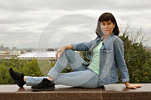 Beautiful European young woman traveler sits on the parapet and enjoys the views of Moscow. Vrorbievy Gory, view of the Moscow