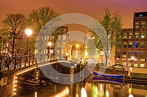 Beautiful evening landscape on the canal in Amsterdam, Netherlands, Europe. Bridge and illumination