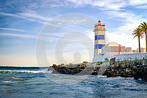 Beautiful evening, sea waves, rocky shores and lighthouse in Cascais, Portugal