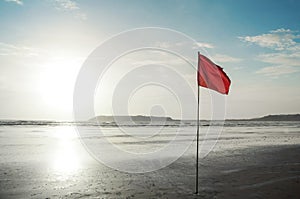 Beautiful evening sky at an isolated beach with red warning flag