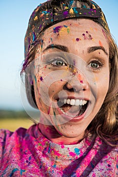 Beautiful excited woman with colorful paint on face and clothes looking away at holi festival