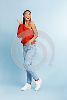 Beautiful excited young woman posing isolated over blue wall background