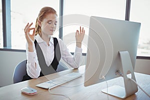 Beautiful executive performing yoga at desk