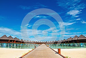 Beautiful exotic beach and wooden bridge to amazing exotic bungalows on turquoise water