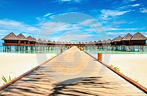 Beautiful exotic beach and wooden bridge to amazing exotic bungalows on turquoise water