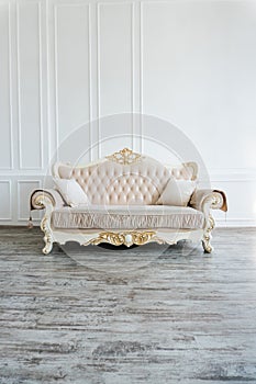 Beautiful expensive beige sofa against a white wall in an empty room