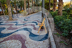 Explanada promenade in Alicante Spain landmark with wooden empty chair on mosaic photo