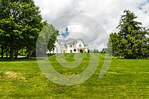 Beautiful exterior of a luxury home on a hill. Yard with green grass and trees