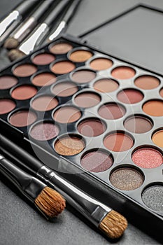 Beautiful eye shadow palette and brushes on dark grey table