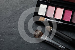 Beautiful eye shadow palette and brushes on dark grey textured table, flat lay. Space for text