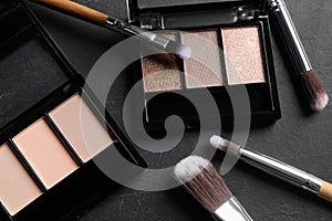 Beautiful eye shadow palettes and brushes on dark grey textured table, flat lay