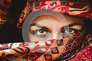 Beautiful eyes. The face of a woman in an red Indian scarf. Expressive look. Oriental beauty