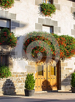 Beautiful facade of old house with flowers. Traditional facade of ancient building in sunlight. Street in mediterranean village.