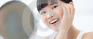 Beautiful face of young asian woman with happy smiling and touch cheek looking mirror with charming.