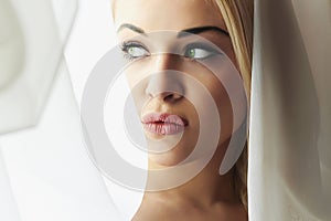 Beautiful Face of Young Blond Bride Woman. Girl Look in Window.Bridal Veil. Curtains