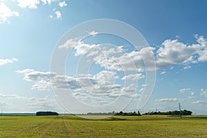 Beautiful fairy-tale clouds over a young farmer\'s field and forest. Neat rows of cereals and traces