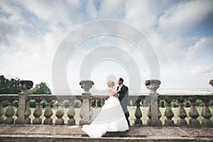 Beautiful fairytale newlywed couple hugging near old medieval castle