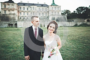 Beautiful fairytale newlywed couple hugging near old medieval castle