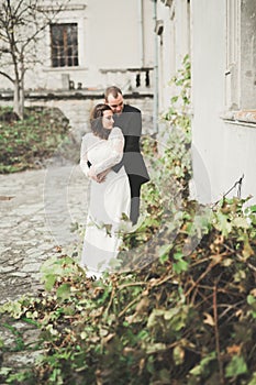 Beautiful fairytale newlywed couple hugging near old medieval castle